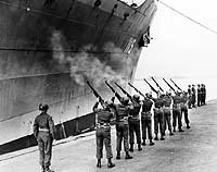 Photo # 80-G-427104:  34th Infantry Soldiers fire a salute as USS General George M. Randall leaves Yokohama with Korean War dead, March 1951