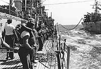 Photo # USN 1134232: Line handlers on USS Boston bring across a fuel hose from USS Camden, July 1968. Photographed by PH2 Gardner, USN